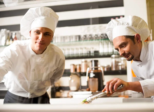 Chef-kok kijken zijn assistent schikken schotel — Stockfoto