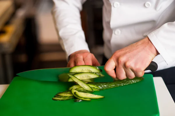 Chef hachant poireau sur planche à découper verte — Photo