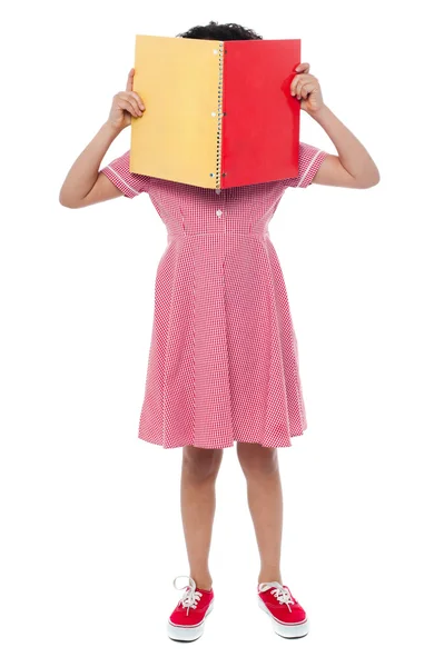 Girl hiding her face behind a book — Stock Photo, Image