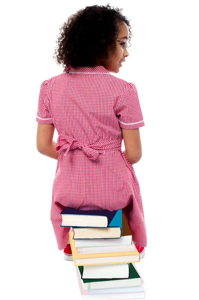 Escola menina sentada na pilha de livros — Fotografia de Stock