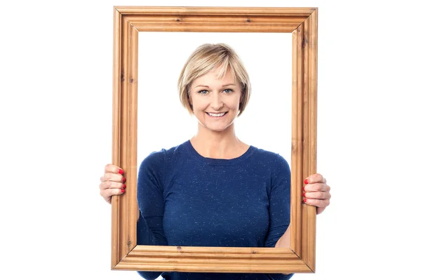 Woman standing behind picture frame — Stock Photo, Image