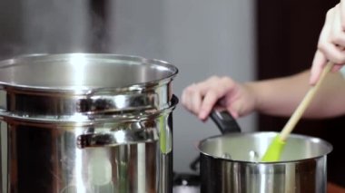 Yemek hazırlıyorum. Eller tencerenin içindekileri kaşıkla karıştırıyor..