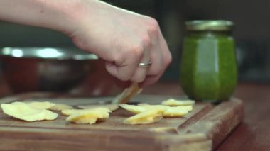 Peynir servisini kapat. Elleriyle peyniri topluyor. Pesto sosu arka planı. 
