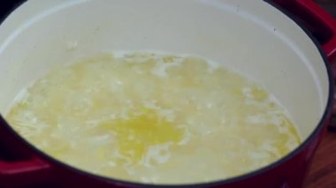 Beyaz pirinç hazırlanıyor. Tavadaki pilavı tahta kaşıkla karıştır ve bir bardak beyaz şarap ekle..