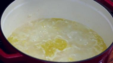 Pirinç hazırlanıyor. Tavadaki pilavı ahşap bir kaşıkla karıştır ve tereyağını ekle..