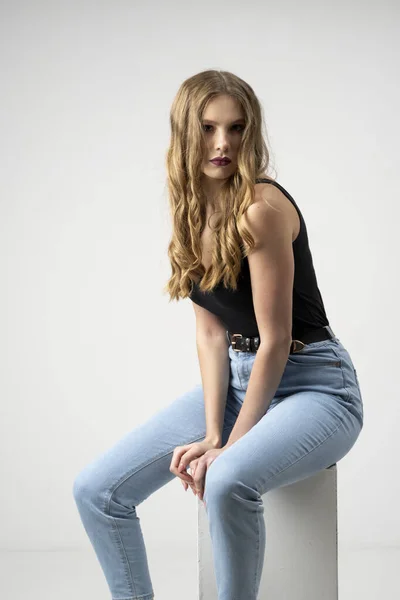 Beautiful young woman portrait in a black t-shirt and blue jeans. Studio shot, isolated on gray background. — Stock Photo, Image