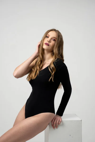 Beautiful young woman portrait in a black bodysuit. Studio shot, isolated on gray background. — Stock Photo, Image