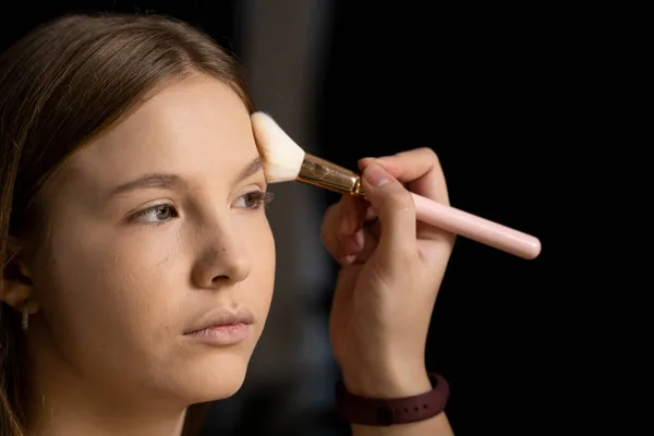 Close up face of beautiful young woman getting powder on her cheek with a brush. Professional makeup artist. — Stock Photo, Image