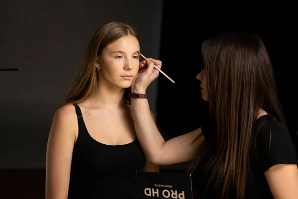 Makeup artist doing a eyebrows makeup on a beautiful woman face. Hand of make-up master is painting eyebrow of young beauty model girl. Make up in process. — Stock Photo, Image