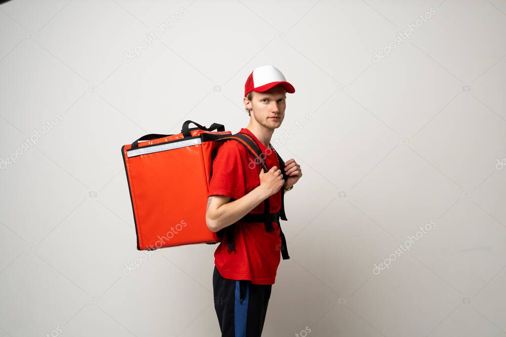 Portraite of delivery man in red t-shirt uniform thermal bag backpack with food isolated on white background studio. Fast Food Delivery Service Cocnept.