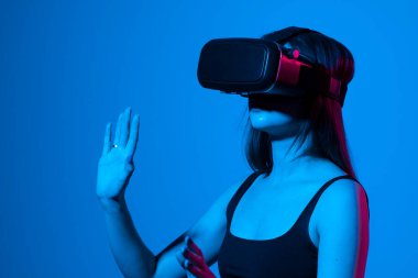 Genç bir kadın simülasyon oyunu oynamak için kulaklık kullanıyor. Sanal gerçeklik 3D video izliyor. VR gözlüklü kız etrafa bakıyor..