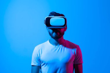 Sakallı adam metaevrenle etkileşim kurmak için kulaklık kaskı kullanıyor. Sanal gerçeklik 3D video izliyor. VR gözlüklü adam etrafa bakıyor..