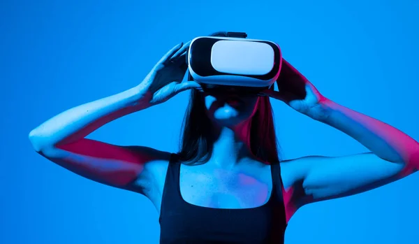 Kvinnelig Amazed i moderne VR-briller samhandler med nettverk mens hun har virtuell virkelighetserfaring. Fremtidig teknologibegrep. Metavers. – stockfoto