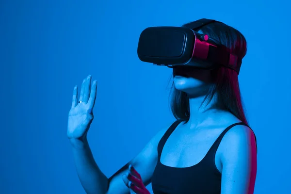 Fiatal nő használ VR fejhallgató sisak játszani szimulációs játék. Virtuális valóság megtekintése 3D-s videó. A lány VR szemüvegben körülnéz.. — Stock Fotó