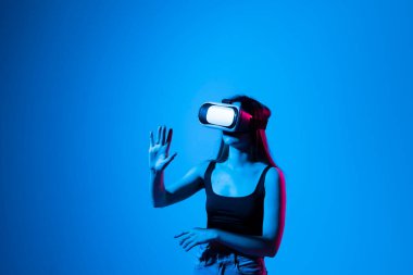 Stüdyoda VR gözlüklü genç bir kadının görüntüsünü yakın plan çekiyoruz. Sanal bir alanda ellerimizle yakınlaşırken metaevrendeki nesnelerle etkileşime giriyoruz. Sanal gerçeklik teknolojisi.