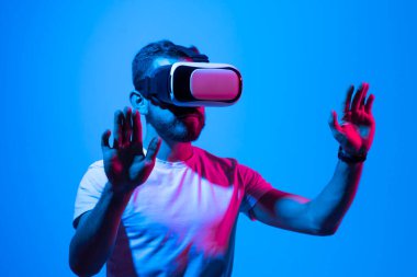 Hayati gerçeklik kavramı. İnsanlar sanal gerçeklikte bir oyun oynuyorlar. Sanal gerçeklik gözlüklü genç adam simülatörde gerçekçi hologramlarla oynuyor. Eğlence ve eğlence konsepti. Modern teknolojiler.