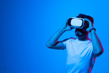 Hayati gerçeklik kavramı. İnsanlar sanal gerçeklikte bir oyun oynuyorlar. Sanal gerçeklik gözlüklü genç adam simülatörde gerçekçi hologramlarla oynuyor. Eğlence ve eğlence konsepti. Modern teknolojiler.