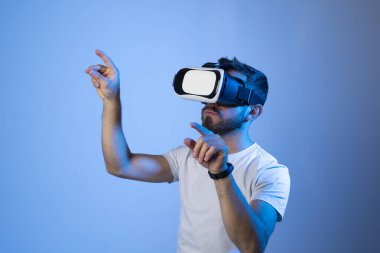 Sanal 3D gözlüklü bir adam stüdyoda hayali bir ekran üzerinde çalışıyor. Evde video oyunu oynayan adam vr gözlük kullanıyor.