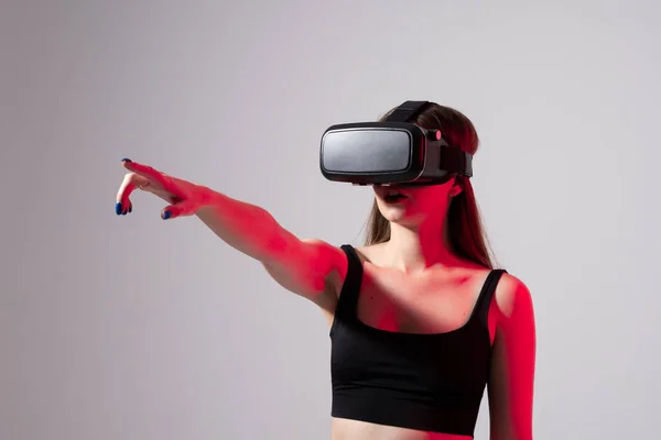 Młoda, przystojna kobieta w wirtualnych słuchawkach i grająca w grę na czerwonym świetle. Podekscytowany hipster w okularach VR. — Zdjęcie stockowe