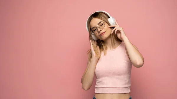 Koncept životního stylu. Portrét krásné ženy v brýlích a růžové košili radostný poslech hudby. Růžové studio pozadí. Kopírovat mezeru. — Stock fotografie