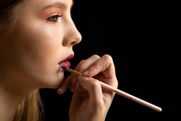 Close up of hand of visagiste applying lipstick on female lips. — Stock Photo, Image