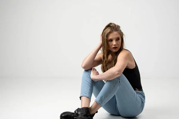 Retrato de mulher bonita jovem em uma camiseta preta e jeans azul. Estúdio tiro, isolado em fundo cinza. — Fotografia de Stock