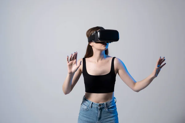 Zbliżenie młoda kobieta stoi w studio w okularach VR i przesuwa przewijanie zooming z rąk w wirtualnej przestrzeni podczas interakcji z obiektami w sieciach społecznościowych. — Zdjęcie stockowe