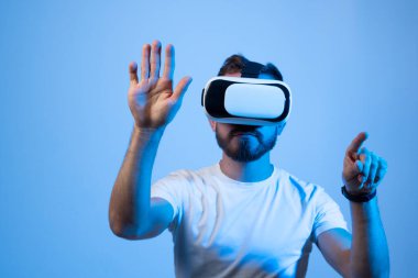 Sanal gerçeklikte video oyunları oynayan gözlüklü genç sakallı adam..