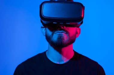 Sanal gerçeklik kasklı genç sakallı adam internette metaverse olarak oyun oynuyor. Oyun kurgusal dünyada davranışları, aletleri ve sanal gerçeklik bağımlılığını taklit eder. Gelecekteki teknoloji konsepti.