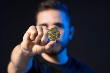 Sanal para basan sakallı genç bir adam. Elinde btc bozuk para tutan bir kripto tüccarı. Kripto para birimi.
