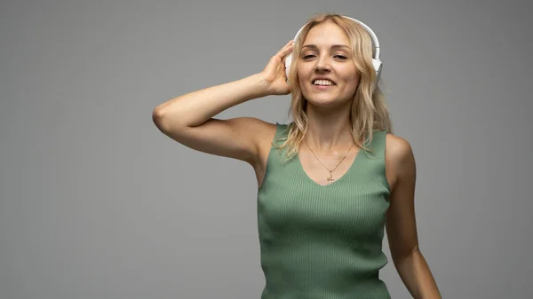 Schöne blonde Mädchen in grünem T-Shirt mit Kopfhörer haben Spaß im Studio tanzen und lachen. — Stockfoto
