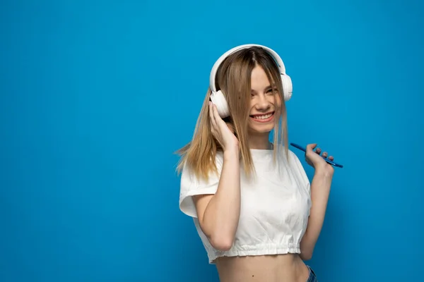 Šťastná mladá blondýna ve sluchátkách s chytrým telefonem poslech hudby. — Stock fotografie