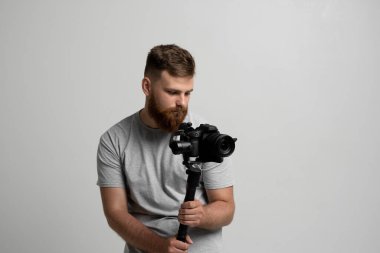 Profesyonel sakallı kameraman kamerayı 3 eksenli telde tutuyor. Steadicam kullanan bir kameraman. Pro ekipmanlar titremeden yüksek kaliteli video yapmaya yardımcı olur.