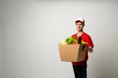 Teslimat Servisi. Kırmızı üniformalı bir teslimatçı. Kurye servisi. Kırmızı termal yiyecek poşetini omzunda tut..