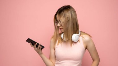 Pembe tişörtlü ve gözlüklü genç sarışın bir kadın telefonla mesaj yolluyor ya da haberci arkadaşlarıyla sohbet ediyor..
