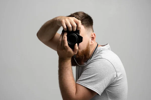 Jóképű és magabiztos férfi fotós egy nagy professzionális dslr kamera, hogy egy kép a fehér háttér. — Stock Fotó