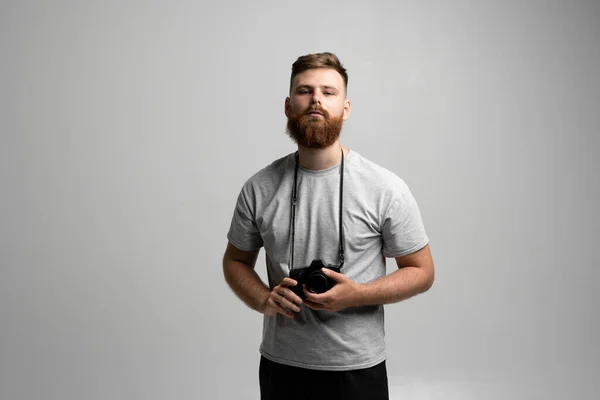 Retrato de fotógrafo profesional barbudo con cámara dslr aislada sobre fondo gris. —  Fotos de Stock