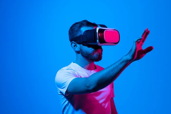 Emocionado hombre barbudo experimentando la realidad virtual a través de auriculares VR y tocando algo con sus manos lo que ve delante de él. Metaverso y juegos. — Foto de Stock