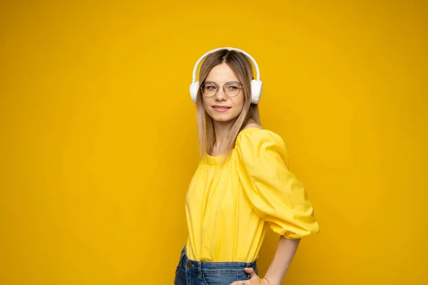 Linda chica joven en camiseta amarilla escuchar música con auriculares. —  Fotos de Stock