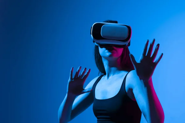 Mujer con auriculares VR mirando los objetos en realidad virtual mientras juega un juego o ve películas en 3D. Concepto de tecnología futura. — Foto de Stock