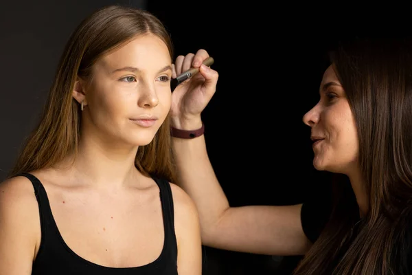 Make-up artist anvender pulver med en børste på modeller kinder. Professionel make-up. - Stock-foto