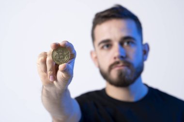 Stüdyoda gri arka planda izole edilmiş Bitcoin 'li siyah tişörtlü başarılı genç iş adamı. Başarı kariyer zenginlik iş kavramı.