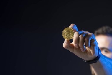 Kripto para birimi konsepti. Sanal para basan sakallı genç bir adam. Elinde btc bozuk para tutan bir kripto tüccarı. Kripto para birimi.