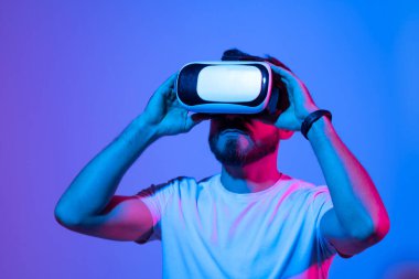 Meta evren konsepti. VR gözlüklü Avrupalı genç adam, sanal gerçeklik kulaklığıyla video oyunları oynuyor, elle bir şeye dokunmaya çalışıyor..