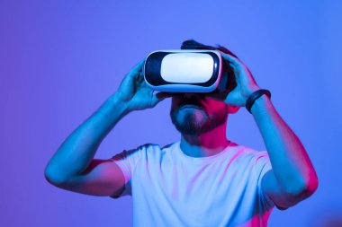 Meta evren konsepti. VR gözlüklü Avrupalı genç adam, sanal gerçeklik kulaklığıyla video oyunları oynuyor, elle bir şeye dokunmaya çalışıyor..