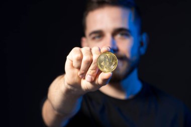 Kriptoholder elinde bir bitcoin tutuyor ve kameraya bakıyor. Yeni sanal para BTC.