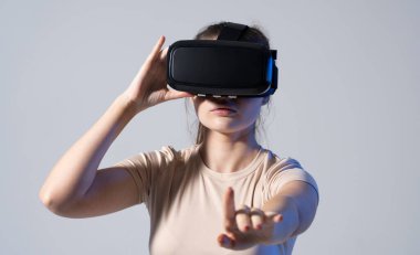 Stüdyoda VR gözlüklü ve elleri havada kaydıran genç bir kadın var. Sanal gerçeklik teknolojisi.