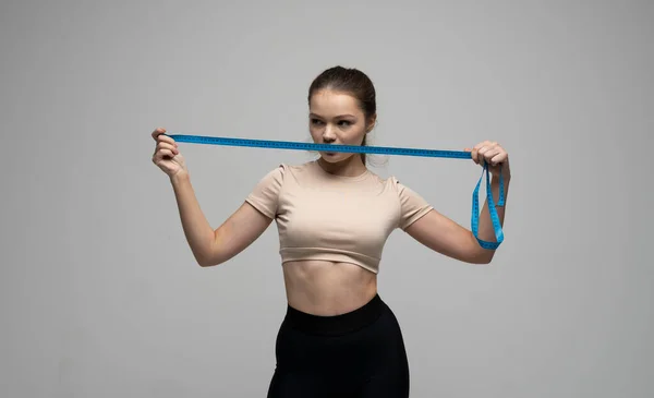 Nádherné zdravé mladé brunetky žena ve fitness oblečení drží měřicí pásku. — Stock fotografie