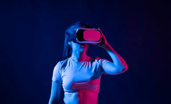 Mujer joven con gafas de realidad virtual y jugando un juego en metaverso. — Foto de Stock