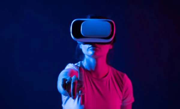 Concepto de tecnología de realidad virtual. Retrato de mujer joven en el estudio con gafas VR y deslizando desplazamiento con la mano en el aire. — Foto de Stock